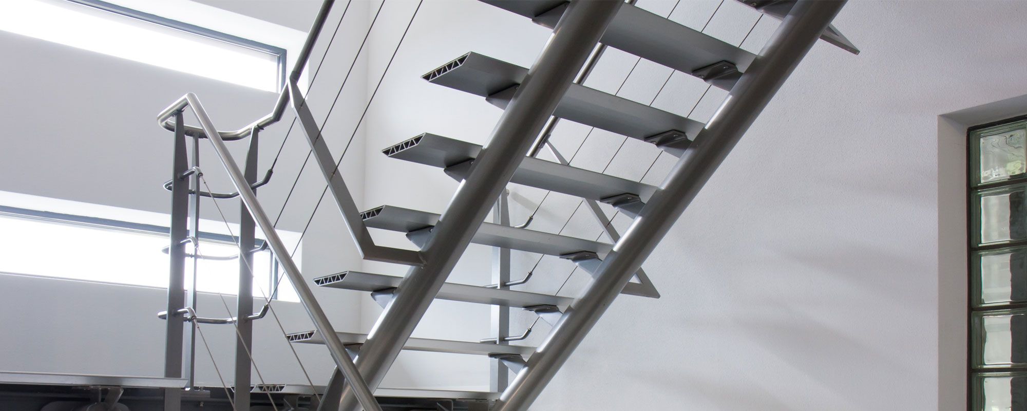 Moderne Metalltreppe mit glatten, offenen Stufen und Drahtgeländer